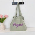 Detail of green waffle fabric tote bag featuring purple Bonjour lettering and drawstring - Grey Green