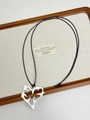 Detail of silver abstract flower pendant on black cord over a wooden display tray - Silver Branch
