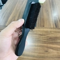 Macro shot of a man's hand holding a curved black wooden beard brush with dense bristles - Short Handle Black Brush 15.6x2.8x2.8CM
