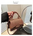 Detail of a brown woven trapezoid handbag with a circular buckle and top handle design - Brown