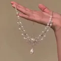 Détail du collier en dentelle argentée avec perles blanches et pendentif goutte - Argent-Motif de Verrou de Longévité