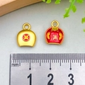 Miniature gold metal Fu bag charms with red enamel alongside a ruler for scale - Money Full Dustpan (12x10mm)