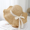 Detail of raffia sun hat with wavy brim and white lace ribbon on a wooden stand - Beige - Wavy Brim Style