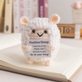 Handmade knitted white sheep doll holding a positive encouragement card on a book - Sheep White