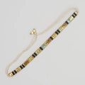 Détail d'un bracelet tissé main avec perles noir mat et turquoise sur cordon blanc - Noir Or Bleu Oxydé Tissé Rétro