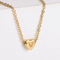 Macro detail of gold-plated heart pendant with letter V engraving on white stand - Letter V