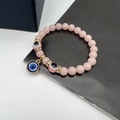 Detailed macro view of pink crystal beads and blue evil eye charms on an elastic bracelet - Luminous Stone Light Pink