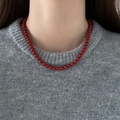 Close-up of vintage red glass bead necklace worn on a grey sweater for a French style look - 6mm / Red