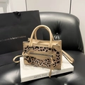 Bolso de mano de leopardo con asas y cremallera de flecos sobre libro blanco - Caqui