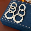 Detail shot of silver hammered metal earrings with three irregular round links on blue box - Triple Interlocking Earrings / Silver