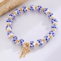 Dettaglio di perle in ceramica bianca e blu con un ciondolo a fiocco dorato e cristallo - Stile Fiocco Perline di Ceramica Blu (1879)