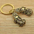 A pair of 3.6cm brass Pixiu keychains for wealth luck on a light wooden background - Pixiu (Left)