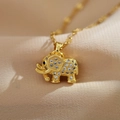 Close-up of golden elephant pendant with sparkling pavé zircons on beige fabric - Gold Elephant
