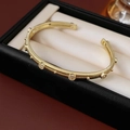 Detail eines vergoldeten, strukturierten Armreifs mit Zirkonia in einer Schmuckschatulle - Gold
