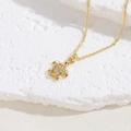 Elegant gold turtle necklace with white flower cubic zirconia on white rock surface - Hollow Flower Turtle Style / Gold