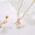 Dettaglio di una collana a coda di pesce dorata con perle e strass su un piatto decorativo - Coda di Pesce / Oro