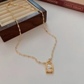 Dettaglio di una collana a grani dorata con intarsio in madreperla e cornice quadra - Oro