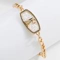 Macro detail of 18K gold-plated zodiac bracelet with white enamel angel and black rhinestones - Angel
