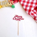 Detail of red Merry Christmas cake topper on white background with festive decor - English Merry Christmas