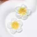 Macro detail of resin frangipani flower charms with white petals and yellow centers - Large White