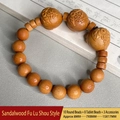 Sandalwood bead bracelet with carved Fu Lu Shou motifs on natural wood texture - Sandalwood Fu Lu Shou Blessing Bracelet