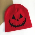 Macro detail of red knitted beanie featuring a black Halloween pumpkin face embroidery - Pumpkin Expression / Red
