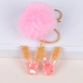 Close-up of pink pompom keychain with resin letter W featuring gold foil and shells - Letter W
