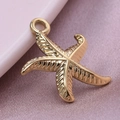 Vista macro de colgante de estrella de mar dorada con textura sobre seda rosa suave - Dorado