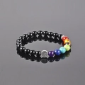 7 Chakra stone tree of life bracelet with black beads on a reflective grey surface - Polished Black Stone Tree of Life 7 Chakra Bead Bracelet