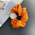 Orologio elastico in seta arancione con quadrante dorato su una rivista di design - Arancione