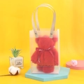 Detail of red bear-shaped towel in transparent gift bag on a blue display stand - Red