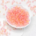Macro shot of pink and yellow frosted gradient glass beads in a white shell bowl - 8mm Yellow Pink Gradient