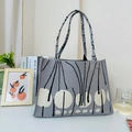 Detail der grauen Stricktasche mit weißen Punkten und schwarzen linearen Pflanzenmustern - Grau