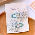 Détail de deux pinces à cheveux artisanales en tissu bleu clair avec flocons de neige - Enveloppé de tissu / Blanc