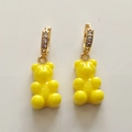 Detail of yellow gummy bear earrings with gold pavé hoops on a beige background - Yellow