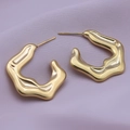 Primo piano di orecchini d'oro in acciaio 18K con design a trama metallica irregolare - Oro