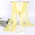 Close-up of semi-transparent thin chiffon scarf in ginger yellow on a metal display stand - Ginger Yellow Solid