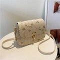 Woven saddle bag with green floral embroidery and adjustable strap on a white table - White