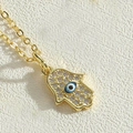 Close-up of golden Hamsa hand pendant with sparkling zircons and blue evil eye detail - Black Palm Type 2