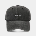 Gros plan de la broderie LOW KEY blanche sur une casquette de baseball grise délavée - Réglable / Noir