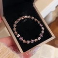 Primer plano de pulsera de flor en oro rosa con circonitas púrpuras en caja negra - Pulsera-Oro Rosa