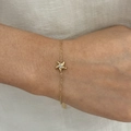 Golden starfish bracelet with sparkling zircon stone on a female wrist close-up view - Gold Bracelet (B871)