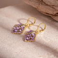 Close-up of vintage geometric diamond earrings with purple crystals on a stone surface - Purple Rhinestone Rhombus