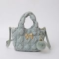 Detail of grey quilted nylon bag with golden bow hardware and plush ball charm accessory - Grey Blue