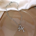 Silver dual cross necklace with sparkling white zircons on a silky fabric background - Silver Cross