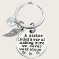 Detail of engraved sister keychain with white pearl and feather charms on a silver metal ring - Heart Style