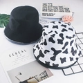 Detailed top view of reversible black and cow print bucket hats with minimalist props - M / Black and White Cow Print