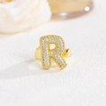 Dettaglio macro dell'anello dorato lettera R con cristalli e gambo regolabile - Lettera R