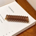 Élastique spirale ambré résistant avec fermoir doré posé sur une page de livre - Café Gelée