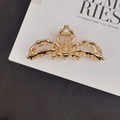 Top view of a gold spider-shaped metal hair claw clip on a stylish magazine background - Exquisite Spider Hair Claw / Gold